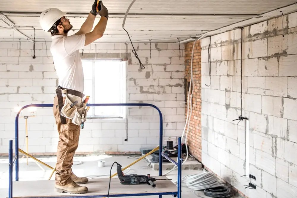 interlocuteur unique supervisant une rénovation de maison de caractère à Guéthary : chef de chantier en discussion avec un maçon devant une villa en travaux
