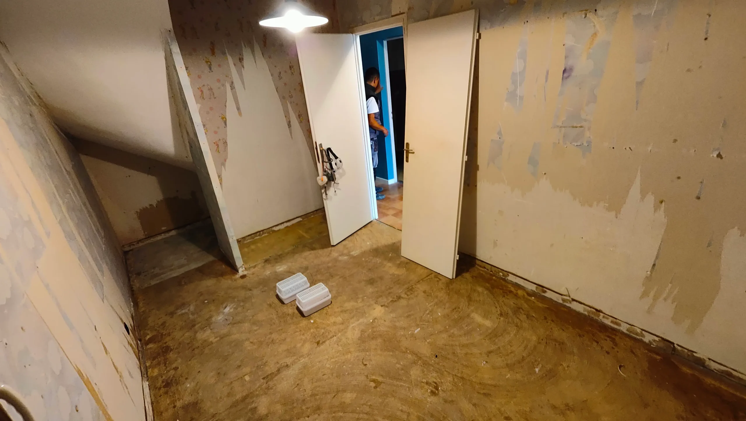 Habitación antes de la reforma del suelo en Saint-Jean-de-Luz — solera deteriorada con manchas de humedad y paredes con papel pintado arrancado