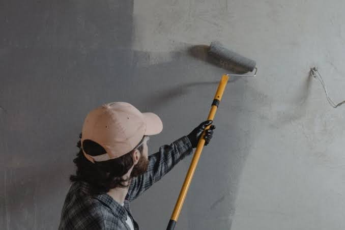 technicien évaluant un mur avant peinture à Hendaye : technicien grattant une zone de mur pour vérifier l'état sous l'ancienne peinture