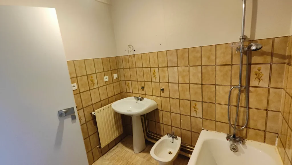 Salle de bain d’origine d’un appartement à Biarritz avant sa rénovation complète : baignoire, bidet et faïence à remplacer, des postes à estimer